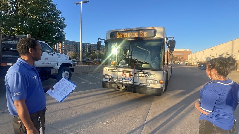 Image of a bus operator trainee in front of a bus with instructor