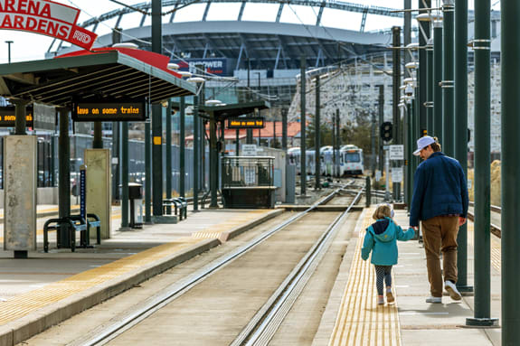 Dad and child walking along a platform with a train approaching