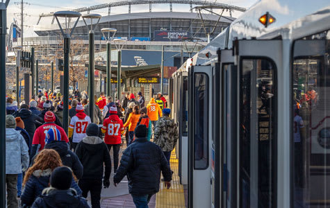 Des clients en tenue des Broncos sortent du train léger à Empower Field.