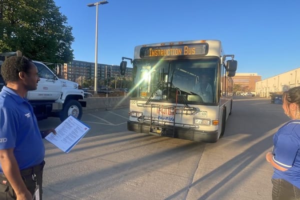 Image of a bus operator trainee in front of a bus with instructor thumbnail