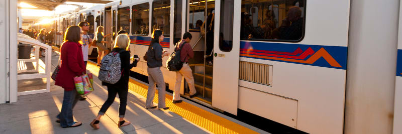 People boarding the lightrail on an early sunny morning