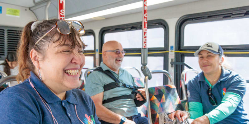 Three customers seated on the bus smiling
