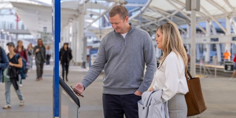 Customers tap their mobile wallet on a rail validator at Denver Union Station