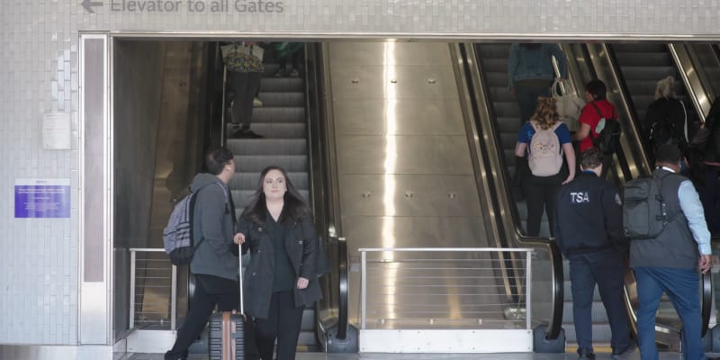 Customer walking to the rail platform with the Airport escalators behind her