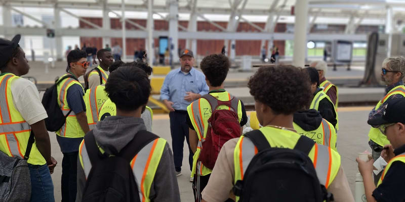 A photo of students standing with DTP GM Nate Morgan on the commuter rail platform at Union Station