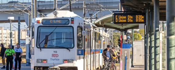 Light rail train pulling into a station with customers waiting to board