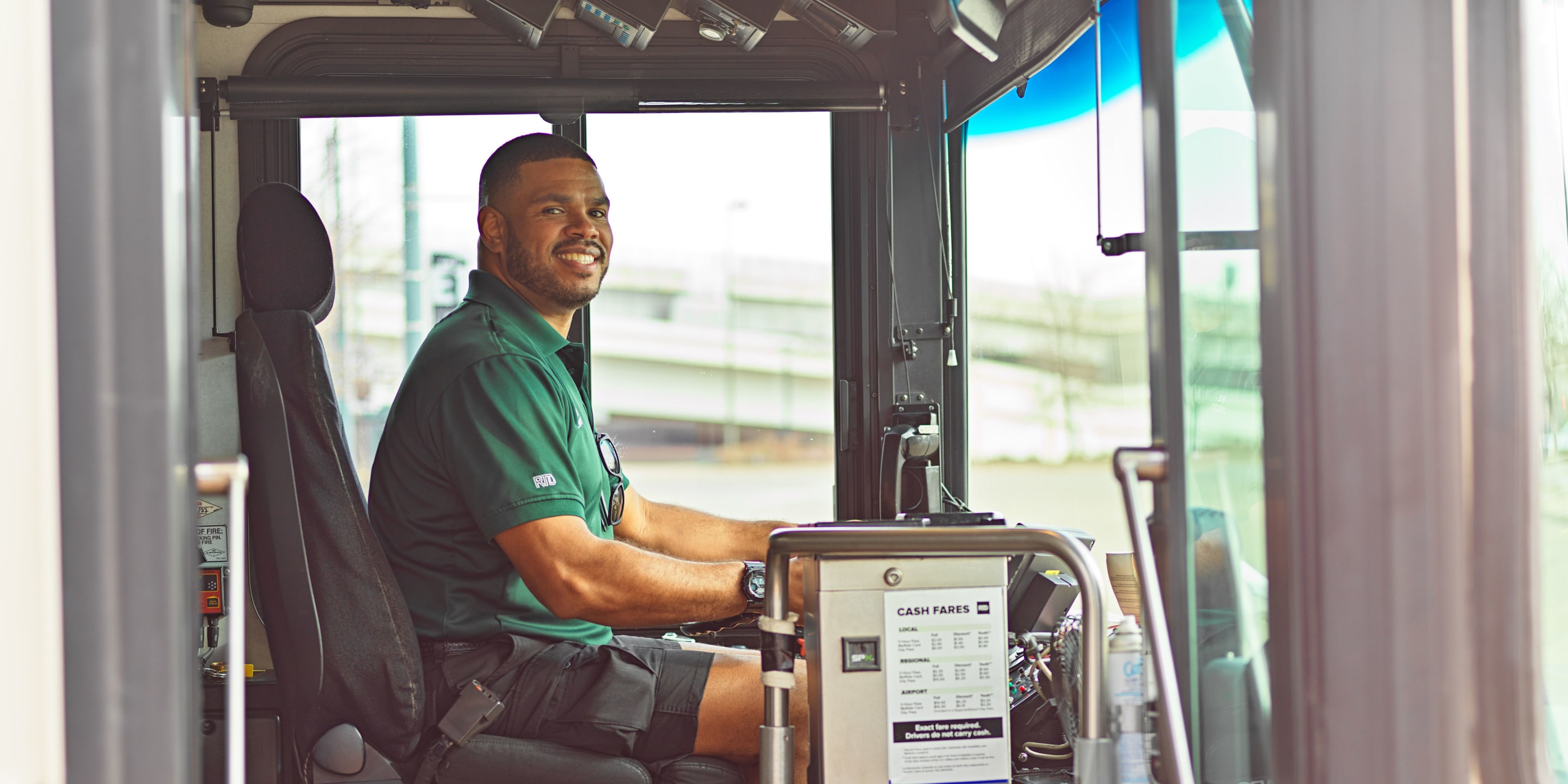Photo of a RTD bus operator sitting in the driver seat smiling for the camera