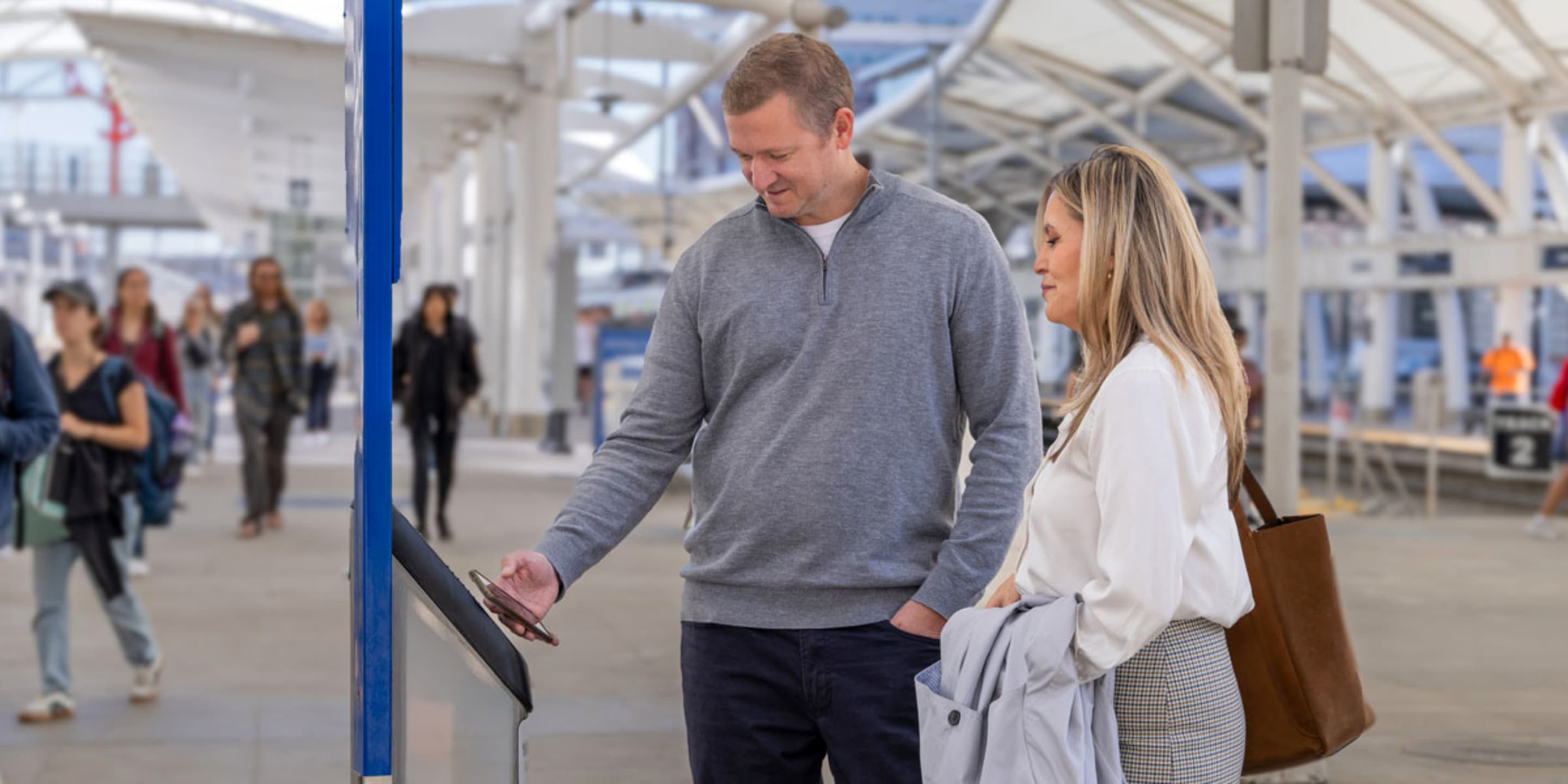 Customers tap their mobile wallet on a rail validator at Denver Union Station