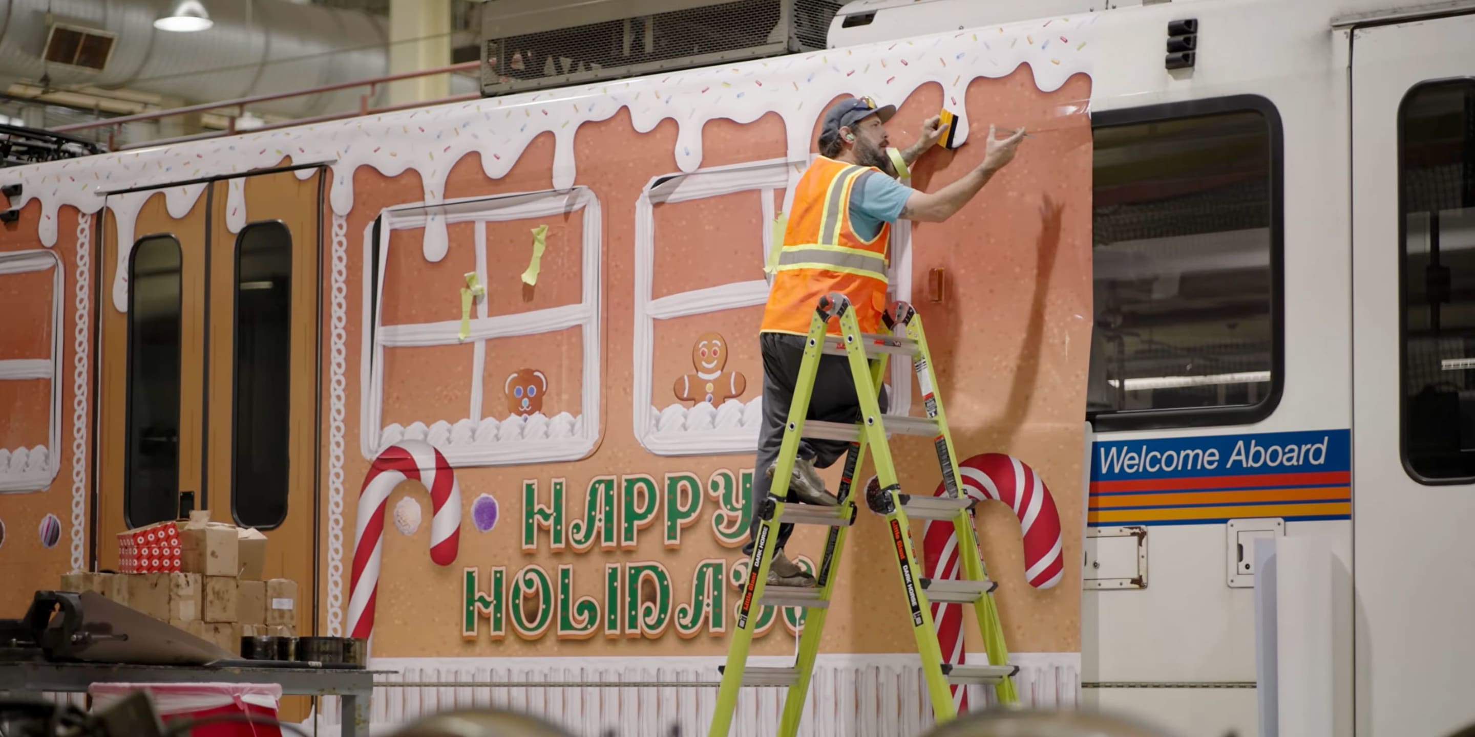 Employee installing a gingerbread wrap on a light rail vehicle