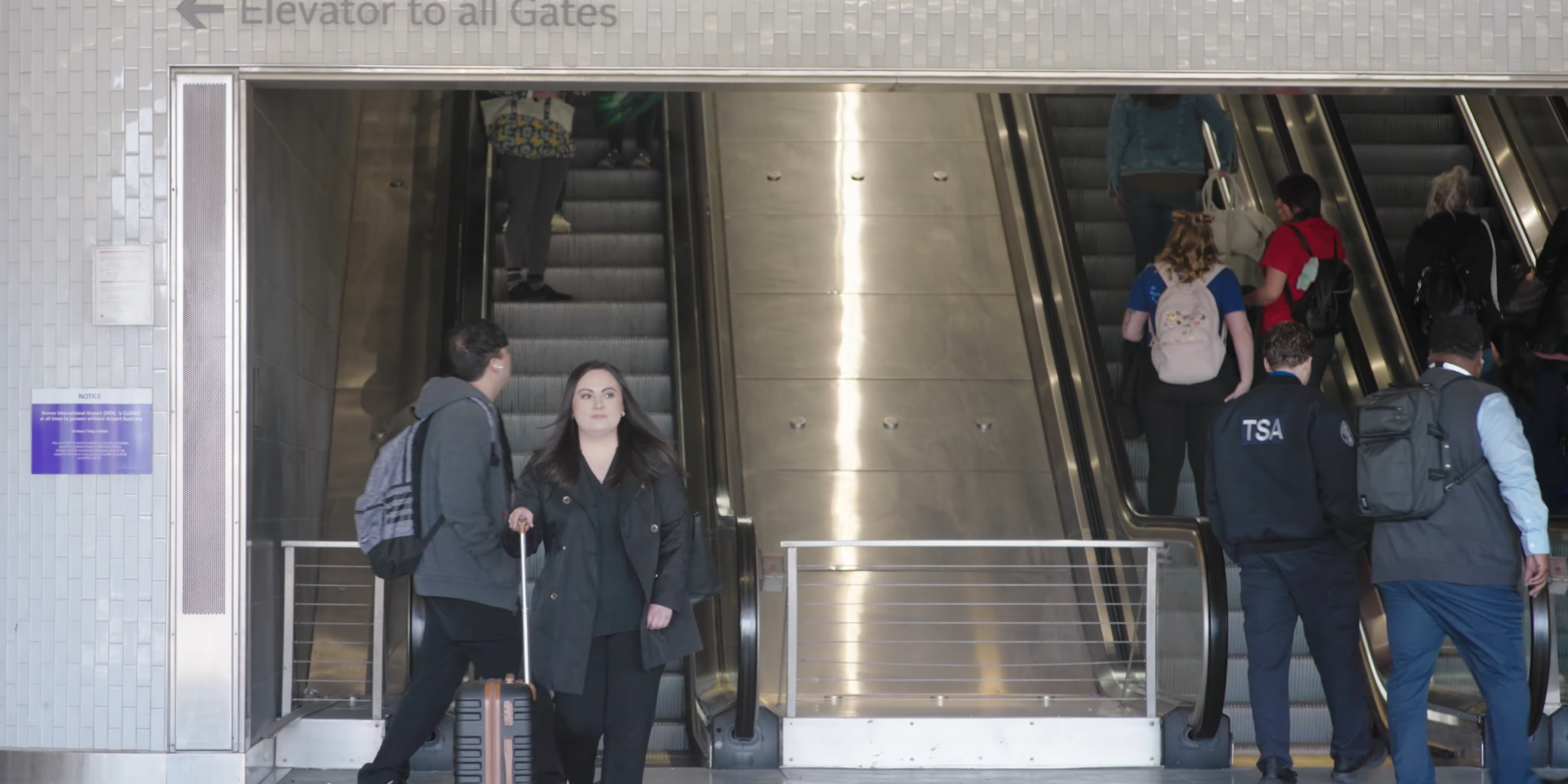 Customer walking to the rail platform with the Airport escalators behind her