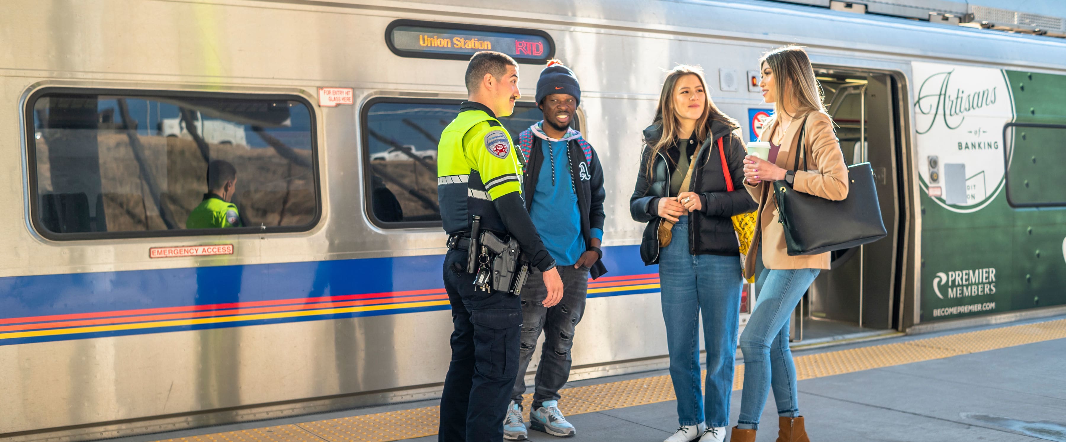 A security officer talks with a group of customers in front of the A line commuter rail