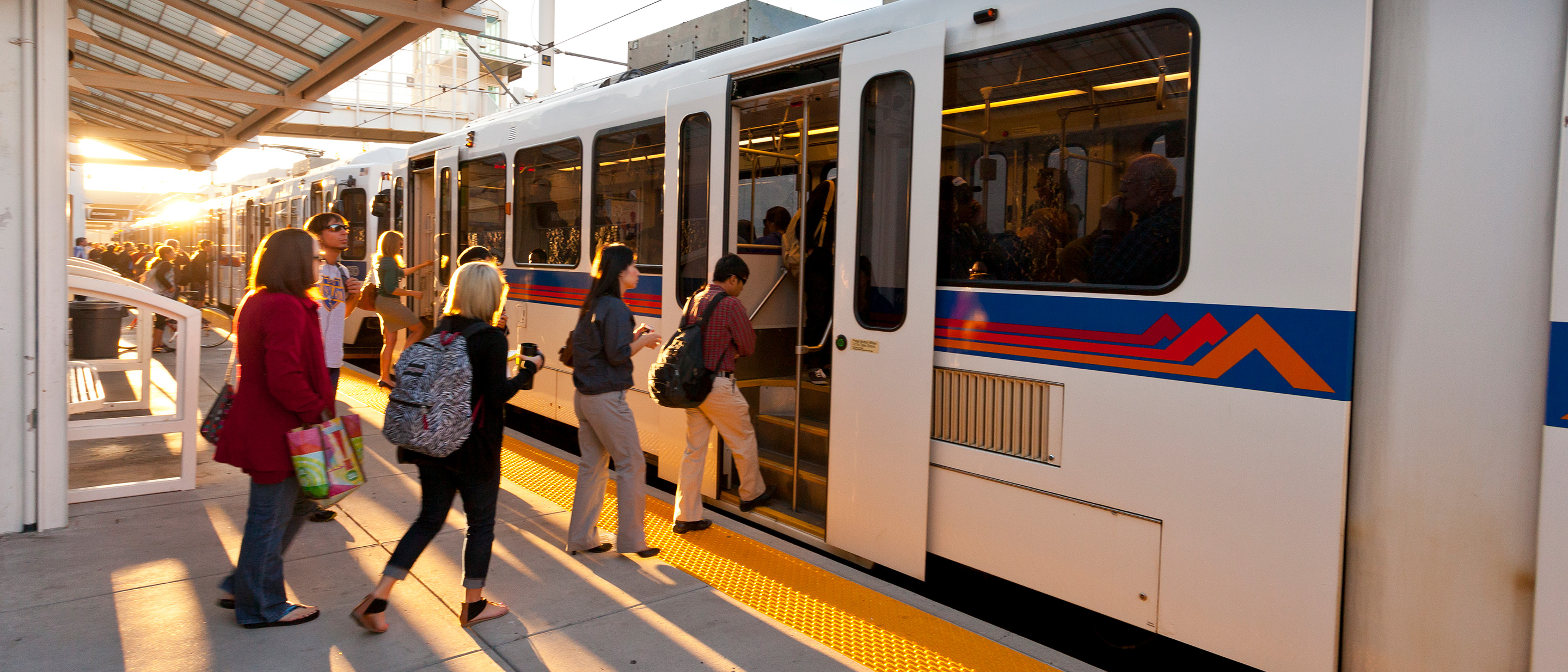 People boarding the lightrail on an early sunny morning