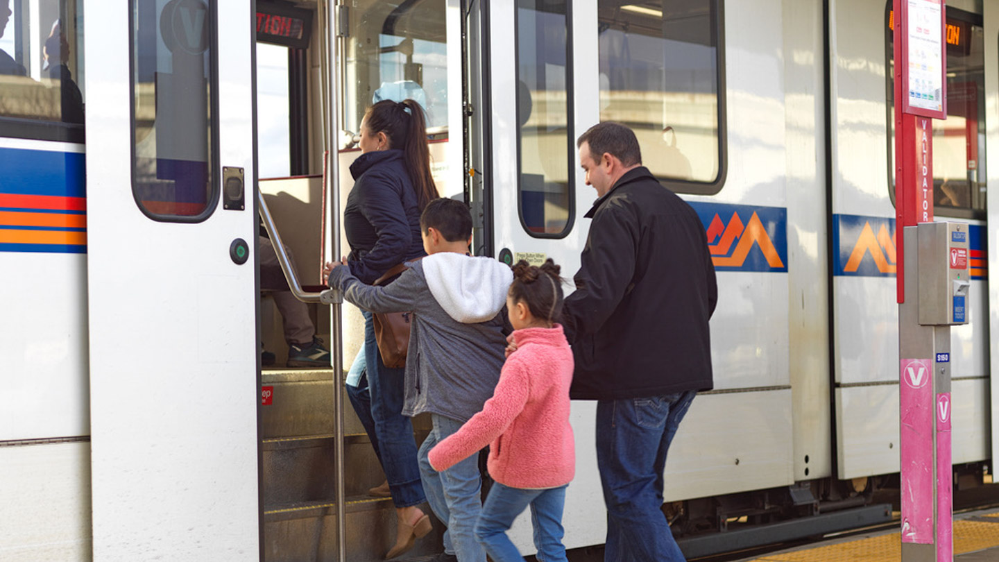 Two children with their parents board the light rail