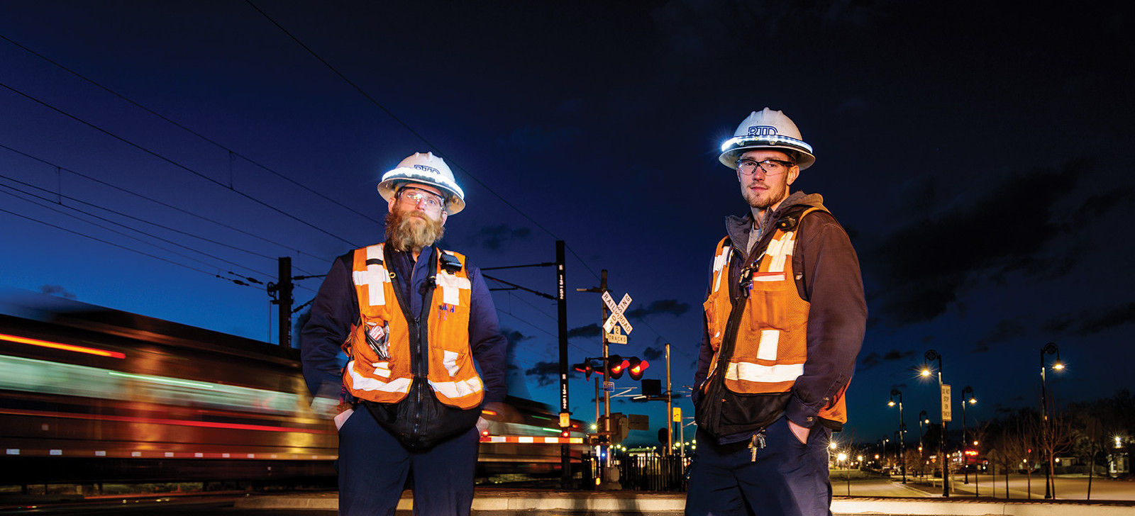 RTD Light Rail Maintenance Employees pose for a photo next to a moving train.