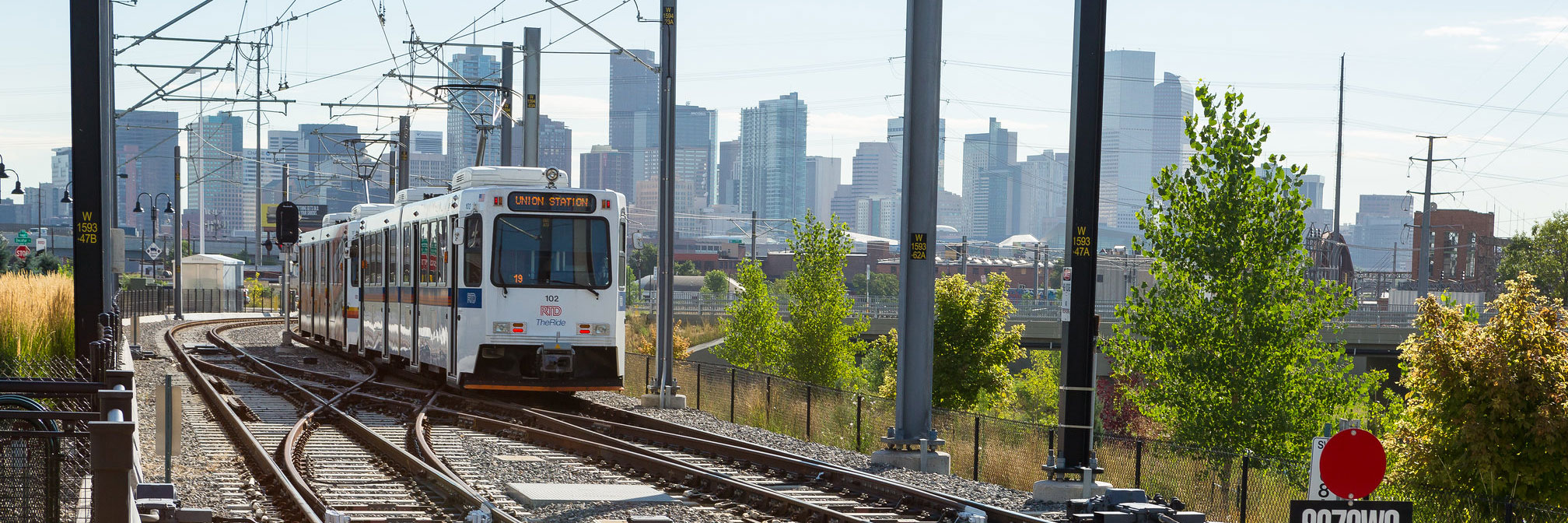 Light rail train with the Denver skyline behind it