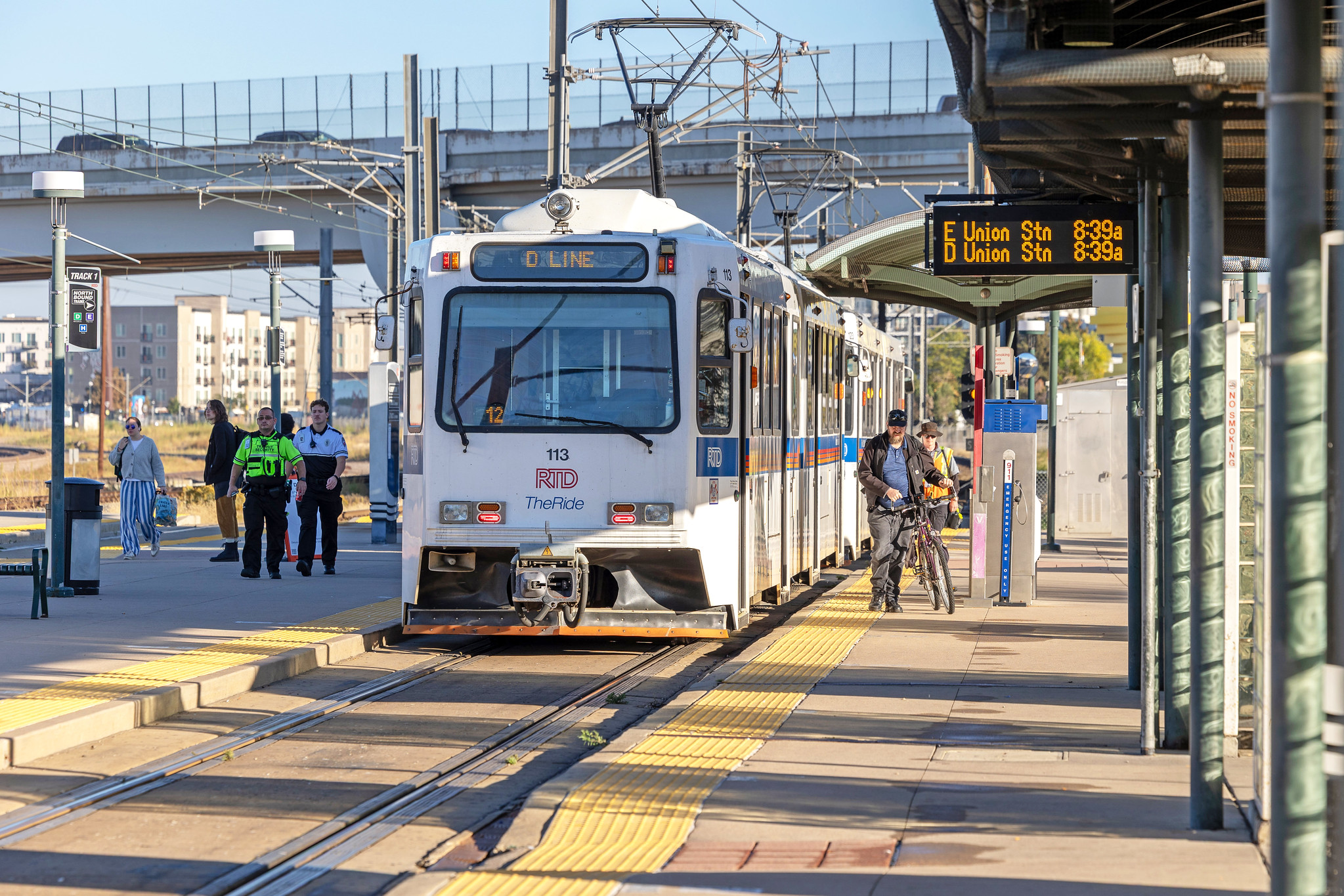 Light rail train pulling into a station with customers waiting to board